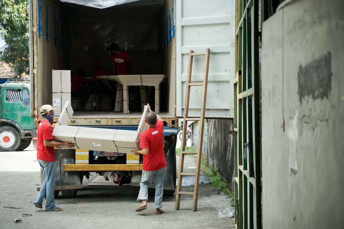 HAFA Cargo staff lifting a wrapped table out of a truck at the warehouse gate.