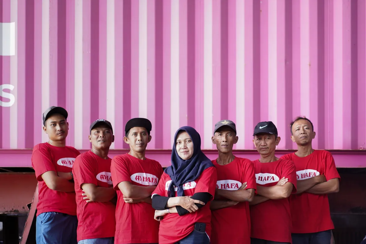 El equipo de HAFA Cargo, siete personas con camisetas rojas de HAFA, delante de un contenedor marítimo.