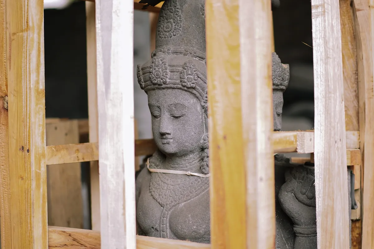 A carved stone figure packed inside a timber crate.