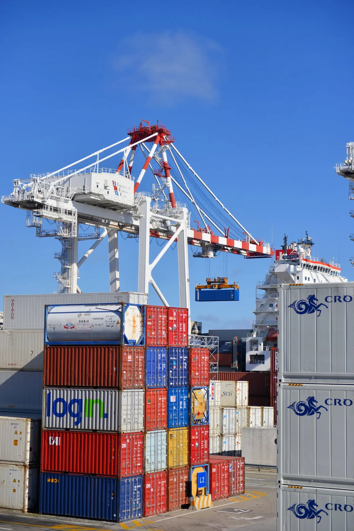 Stacked shipping containers under a port crane.